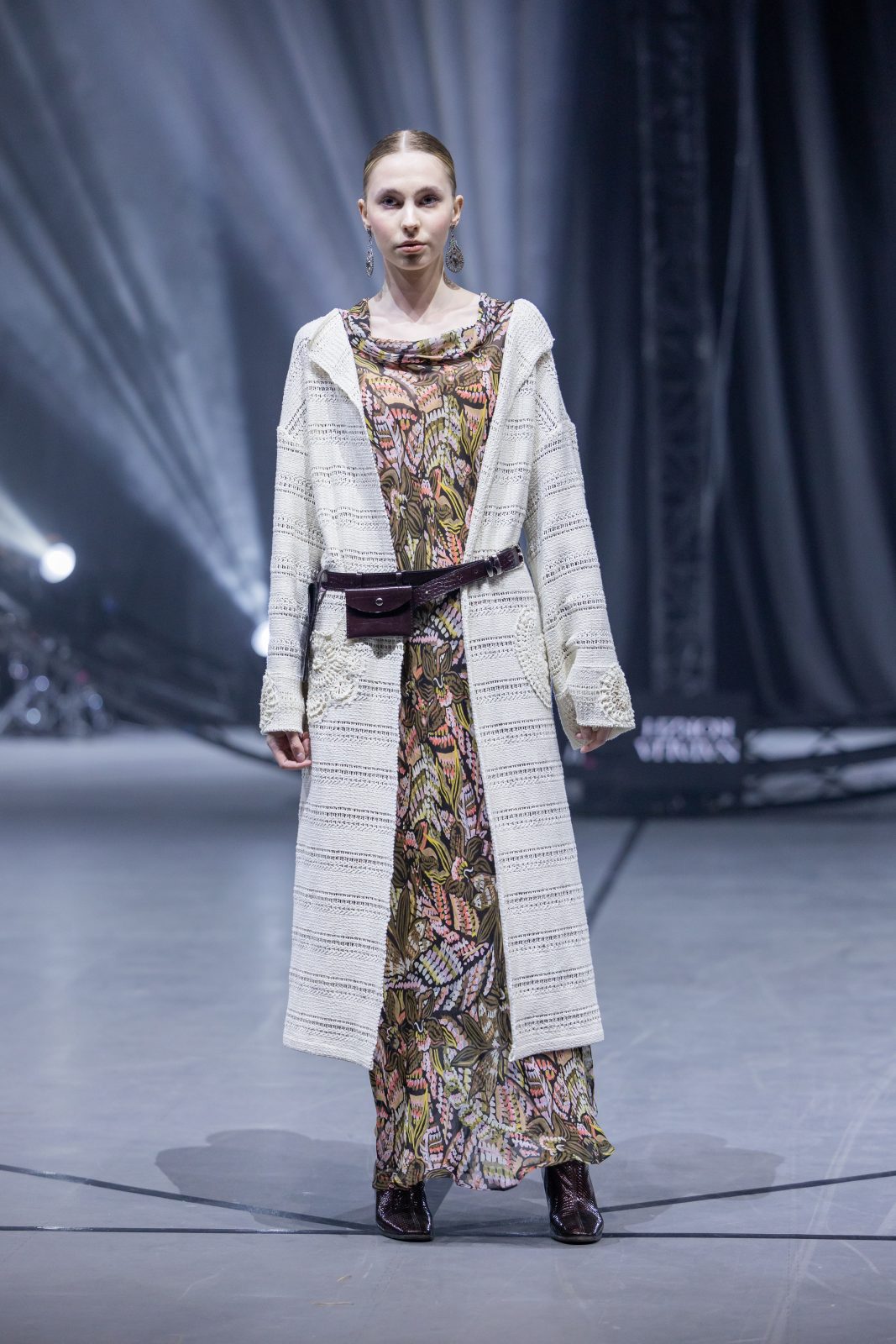 Модель на подиуме в стильной одежде в рамках Belarus Fashion Art Week, фон с ярким светом.